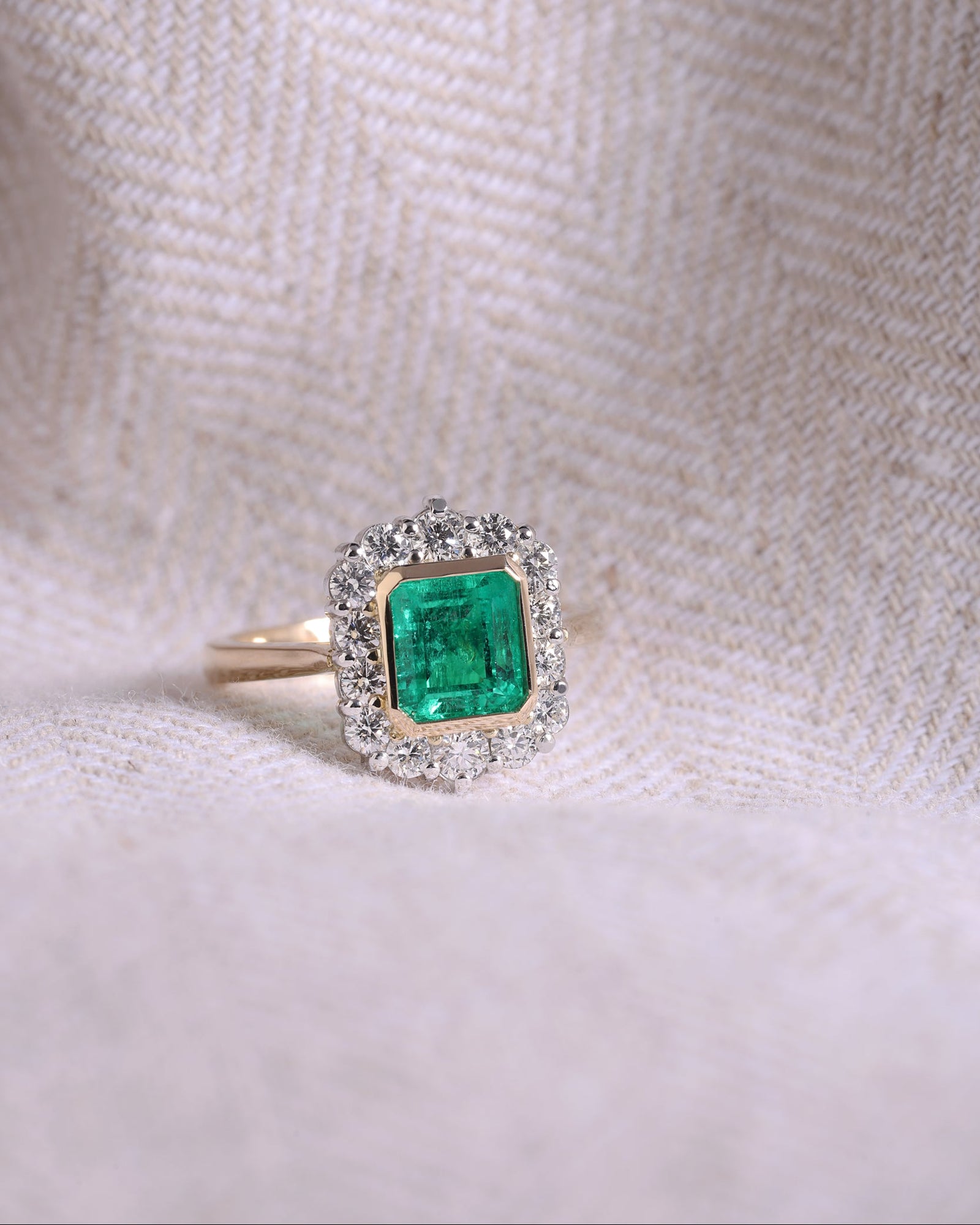 Ring with a green gemstone and diamond-like accents on a textured white background