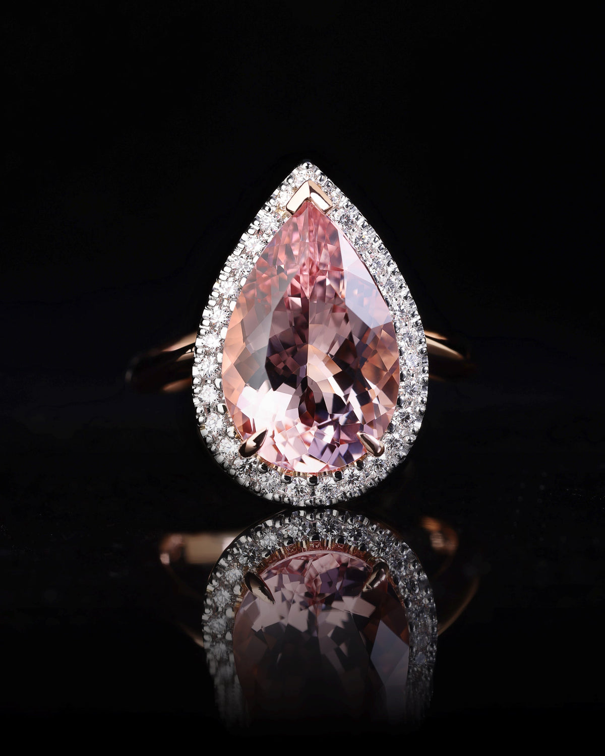 A bespoke Morganite and Diamond ring with a pear cut Morganite gemstone in a platinum setting, surrounded by round brilliant cut diamonds in a rose gold band.