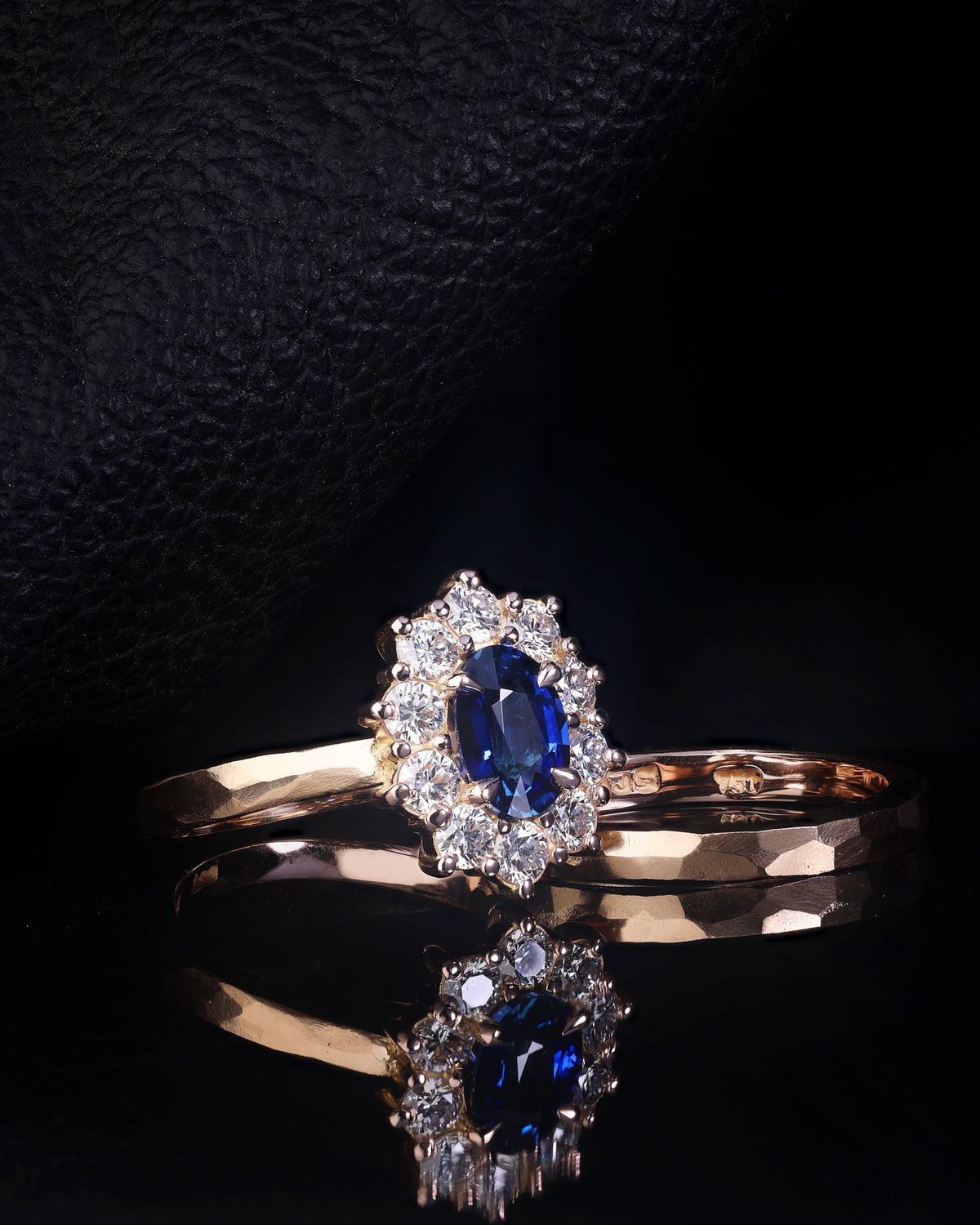 An engagement ring featuring an oval cut blue sapphire center stone with round cut diamonds set in 18ct rose gold, accompanied by a matching wedding band.