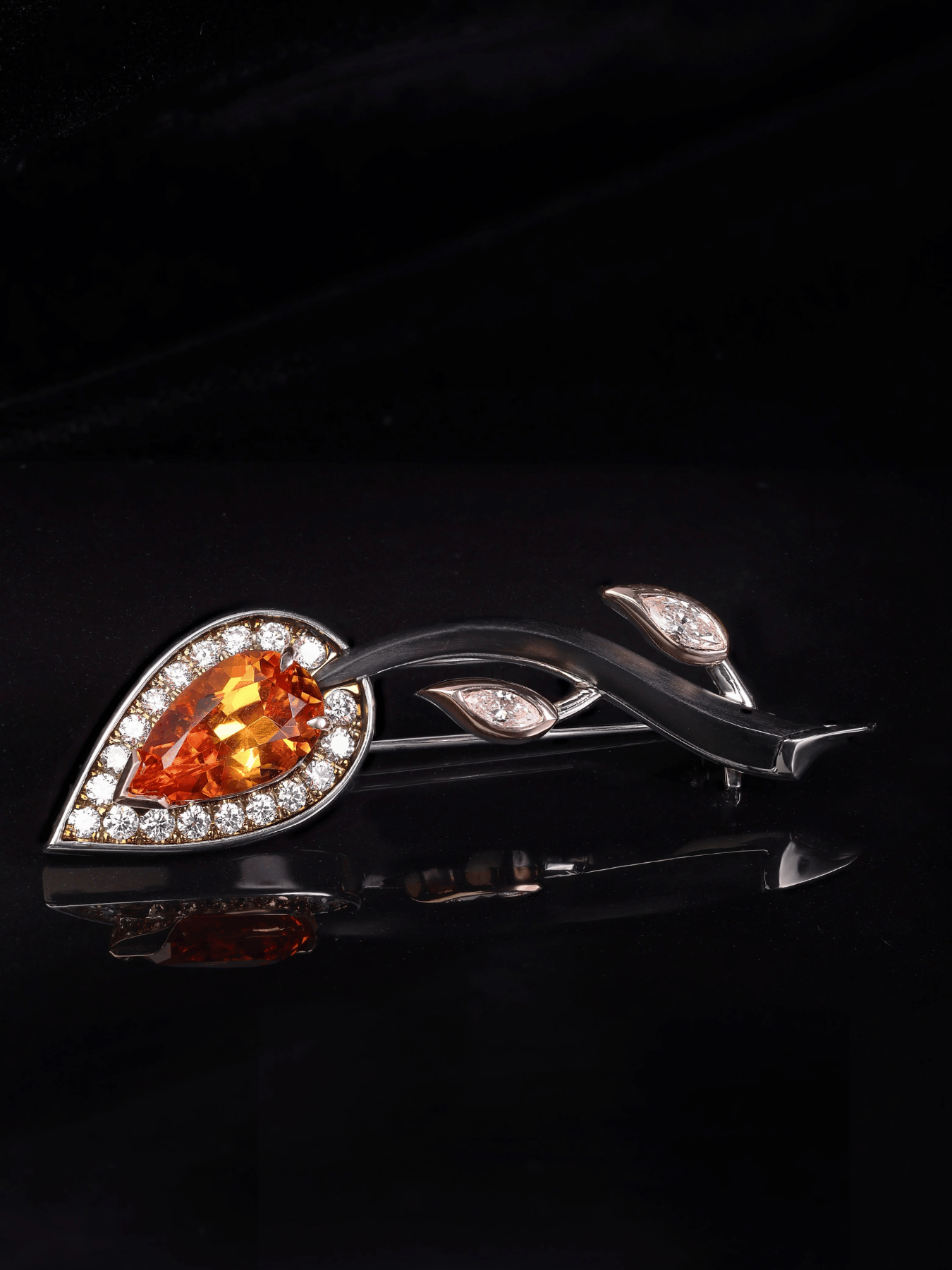 Ornate brooch with orange gemstone on an orange flower against a green background