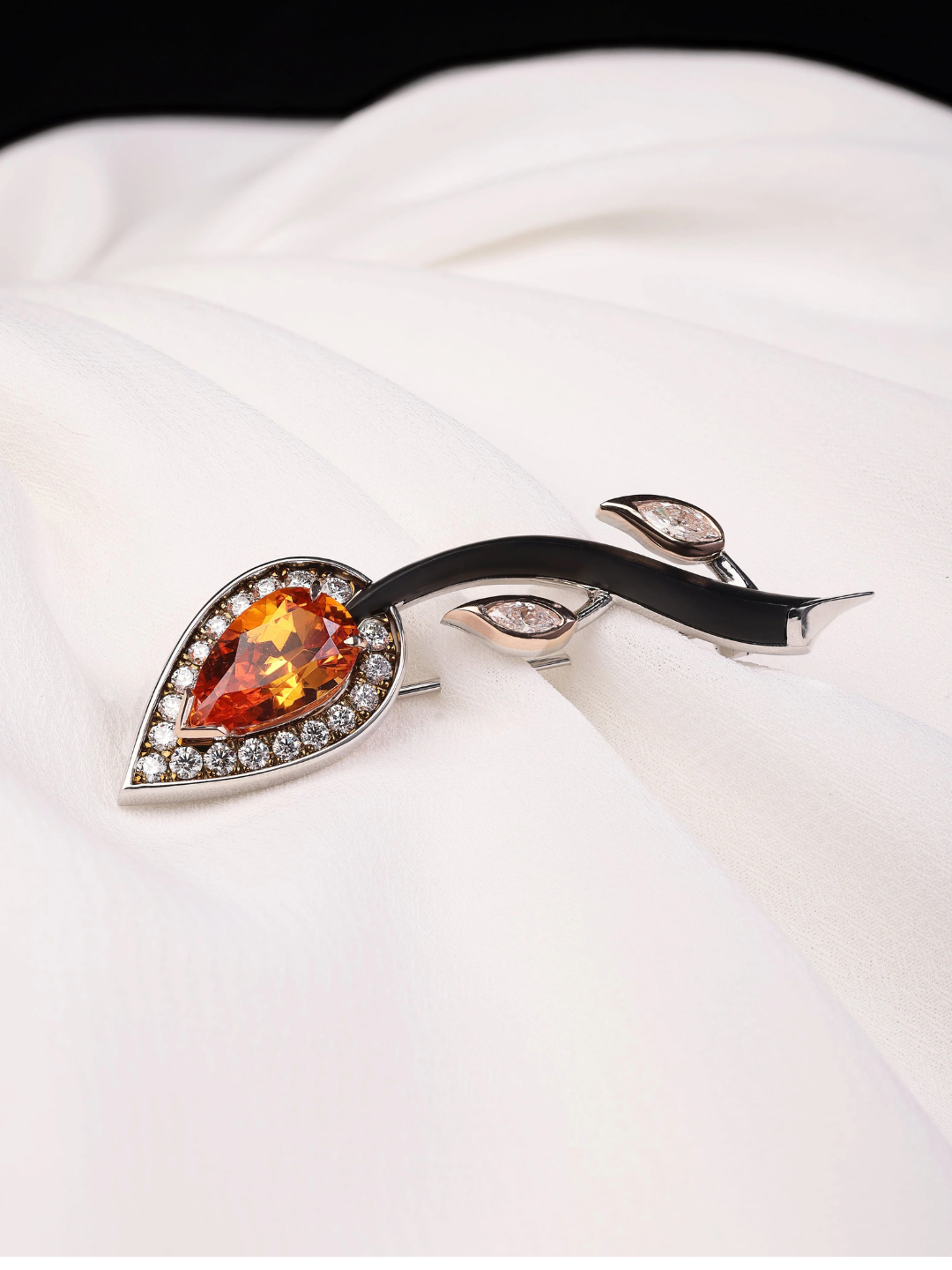 Jewelry brooch with orange gemstone on a white fabric background