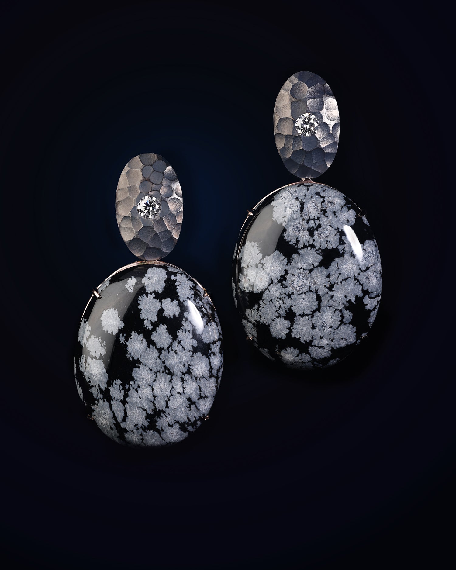 A close-up image of a person wearing 18ct Rose Gold earrings featuring round brilliant cut diamonds and cabochon cut snowflake obsidian gemstones.