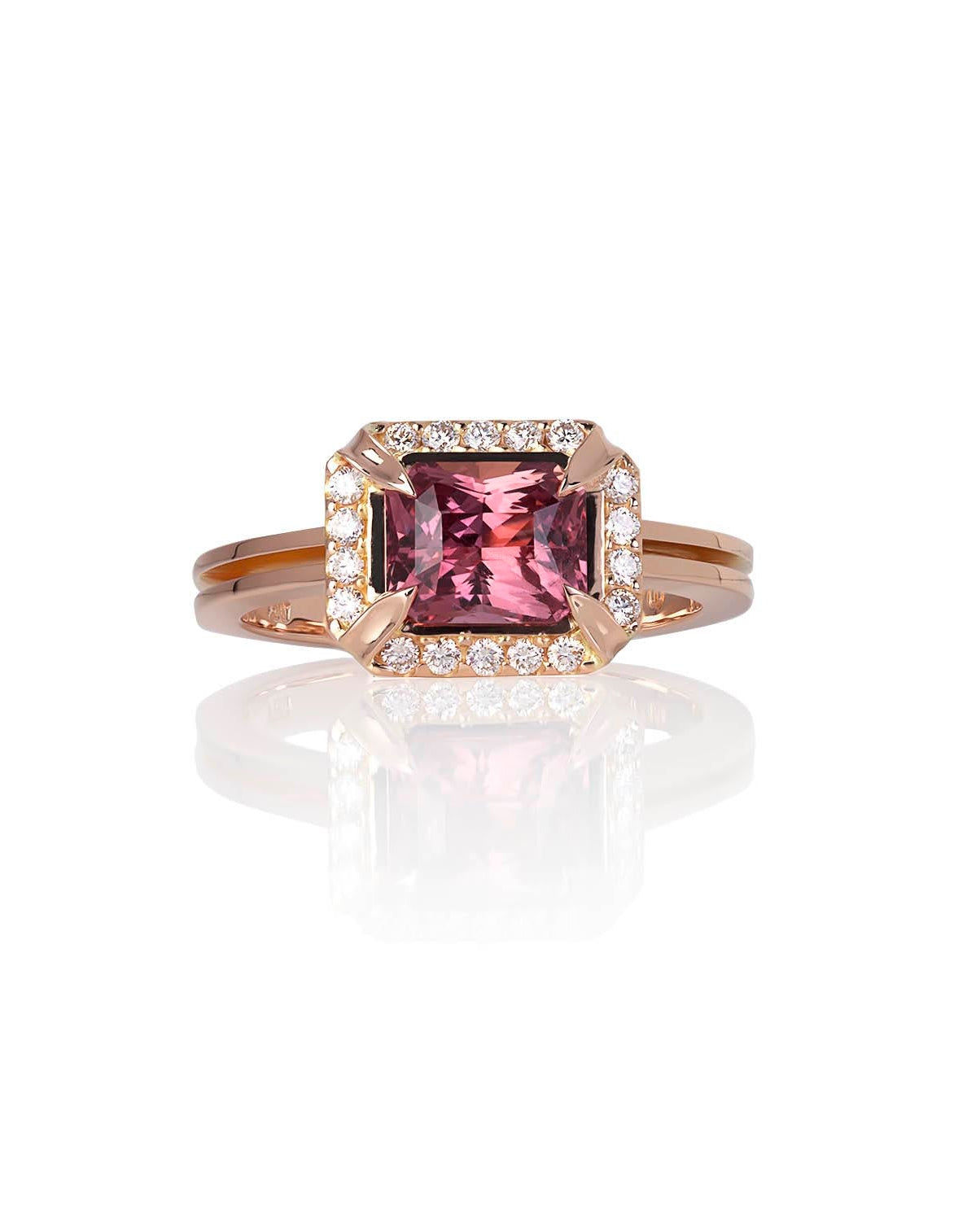 A close-up of a person's hand wearing a 18ct Rose Gold ring with a central Madagascan Cinnamon Sapphire surrounded by a halo of smaller diamonds.